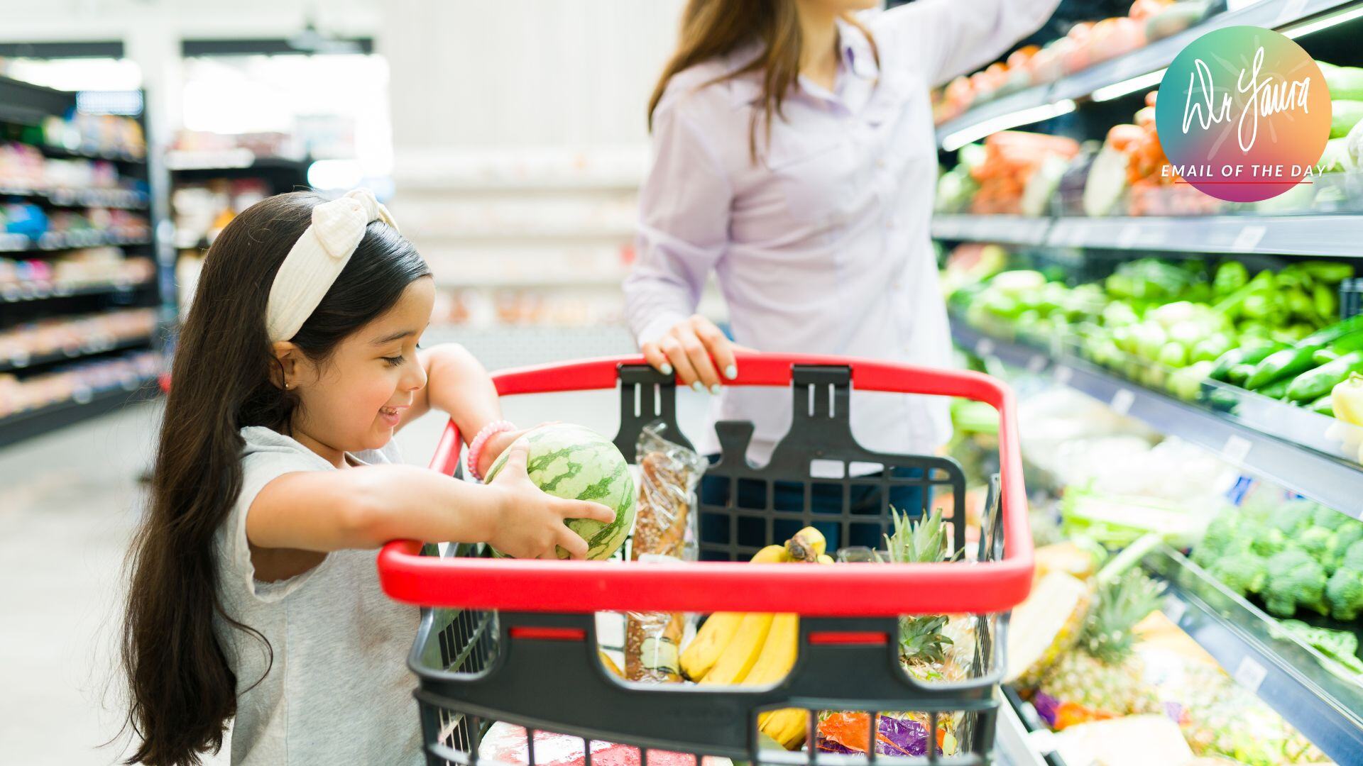 Little girl puts a watermelon in a shopping cart in a grocery store while woman stands behind it