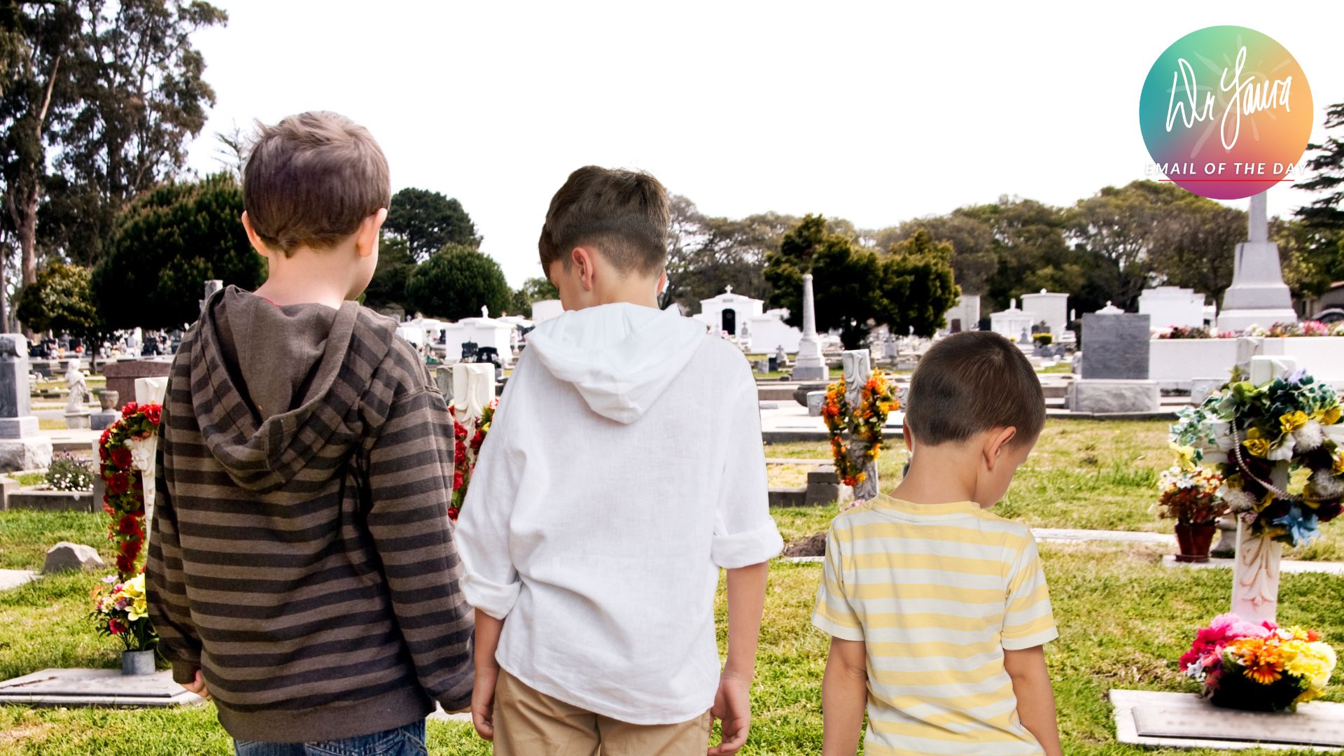 Three young boys stand in a cemetery while looking down